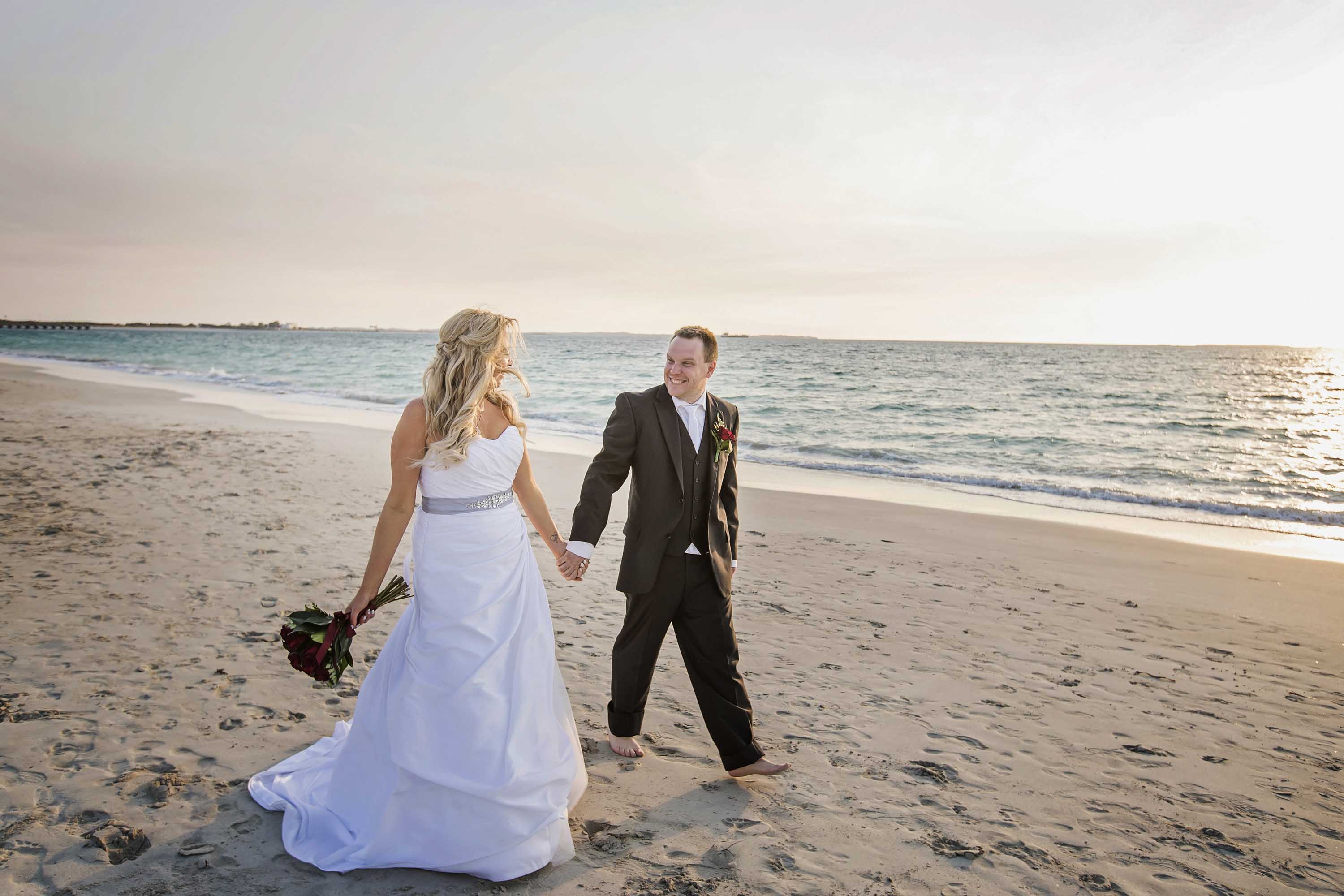 Bride and groom walking on beach outside Coogee beach life saving club